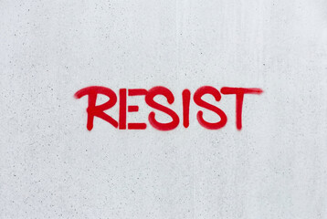 Fototapeta premium The word resist painted in bold red spray paint letters on a clean smooth concrete wall