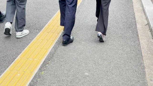 Japanese Businesspeople Walking on Asphalt Sidewalk with Tactile Paving in Tokyo