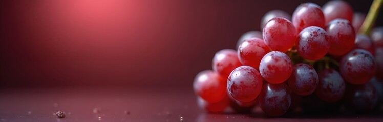Fototapeta premium Close up of ripe crimson grapes on dark red backdrop. Juicy fruit cluster offers sweet flavor and healthy benefits. Perfect for autumn harvest and wine themes.