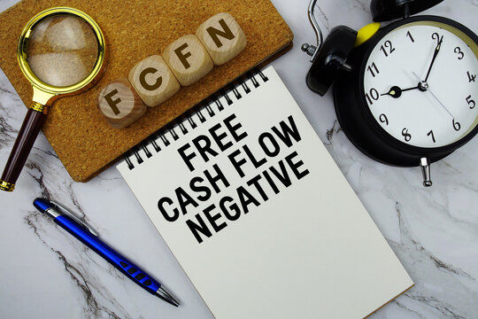 FCFN Free Cash Flow Negative text written on notepad with calculator and magnifying glass on marble background