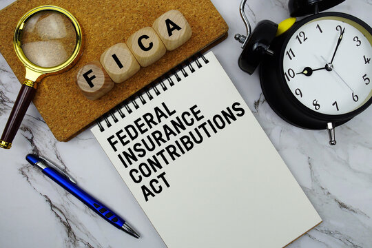 FICA Federal Insurance Contributions Act text written on notepad with magnifying glass and alarm clock on marble background