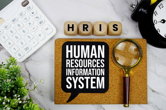 HRIS Human Resources Information System text with calculator, magnifying glass and alarm clock on marble background