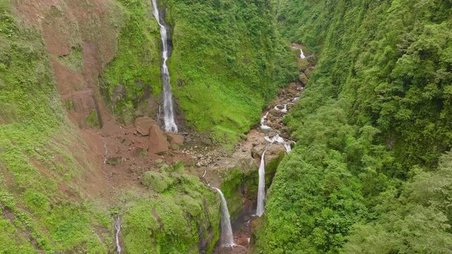 Multi tier waterfall deep in remote Costa Rica rainforest, cascading over moss covered rocks and cliffs surrounded by vibrant tropical vegetation.
