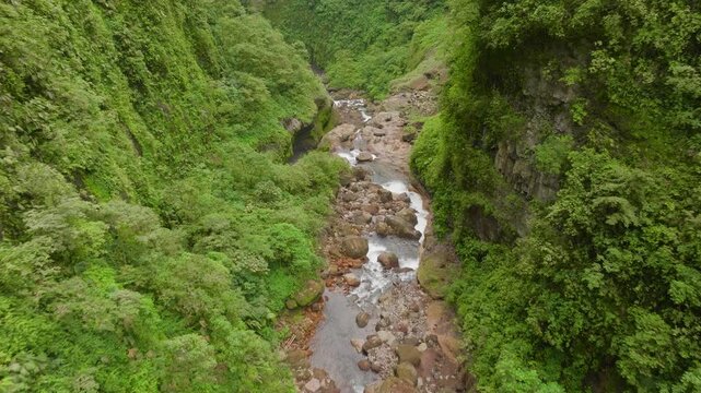 Drone shot of hidden jungle waterfalls cascading through dense green rainforest in remote Costa Rica, far from civilization and surrounded by wild tropical nature.