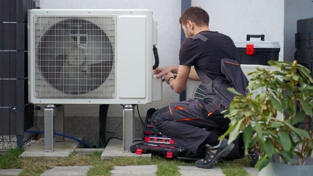 Technician servicing outdoor heat pump unit with tools beside residential house. Concept of HVAC maintenance, home climate control and energy efficient heating and cooling