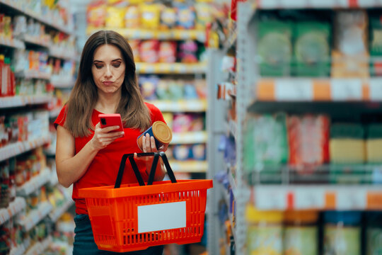 Woman Checking Product Ingredients on the Internet. Woman with shopping basket is confused in a supermarket aisle reading the label
