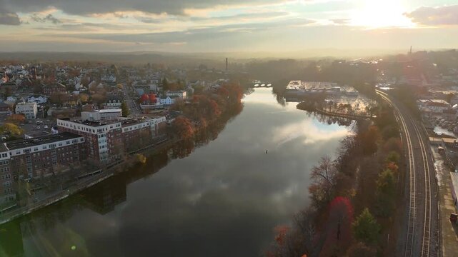flying forward over the Charles River near Waltham, Massachusetts, showing calm water, surrounding urban landscape, and autumn scenery in New England