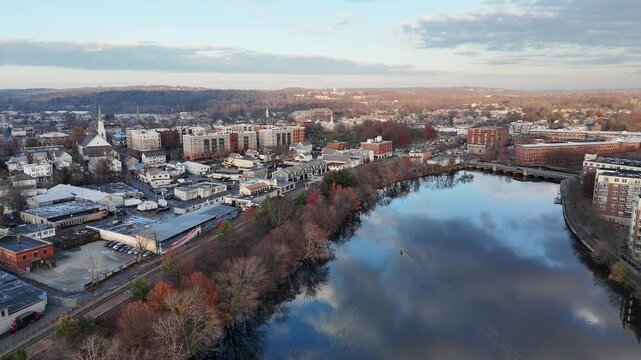 flying forward over the Charles River near Waltham, Massachusetts, showing calm water, surrounding urban landscape, and autumn scenery in New England