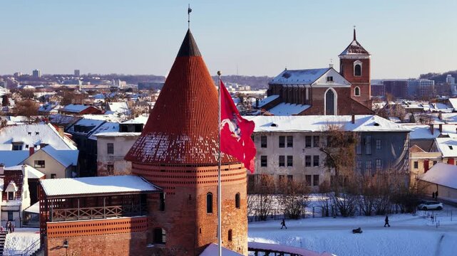 Waving coat of arms flag in Kaunas old town, aerial orbit view