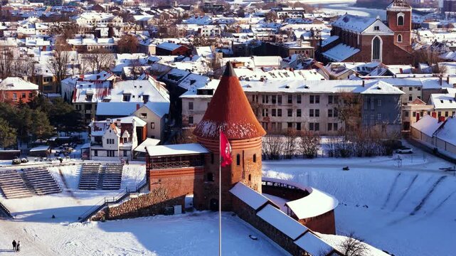 Historical Kaunas castle and waving red Coat of Arms flag, aerial view