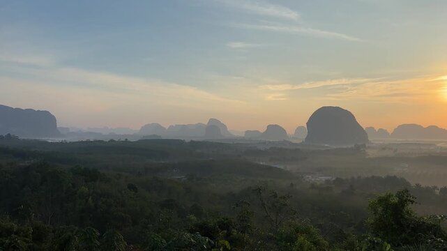 Wide sunrise scene over limestone valley and forest at Din Daeng Doi in Krabi Thailand with soft sunlight, misty layers, distant hills, and calm tropical landscape
