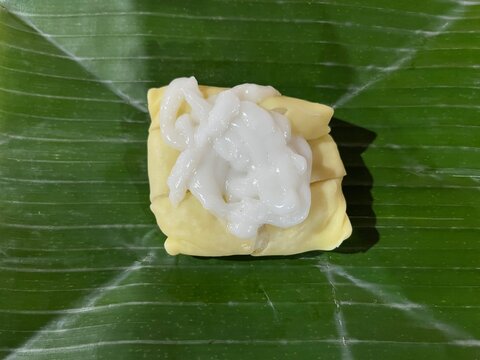 Semar Mendem, a traditional Javanese snack made of glutinous rice and chicken, wrapped in egg crepe and topped with thick coconut milk on a banana leaf.