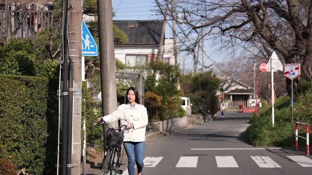 自転車をおしながら横断歩道を渡る女性