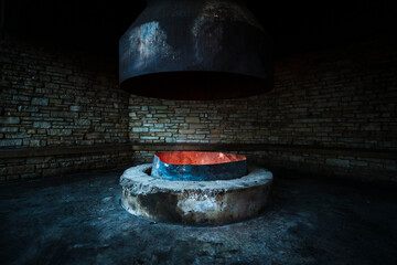 Fototapeta premium Large indoor fire pit inside stone shelter with glowing embers.