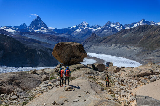 Mountaineers descending towards mountain hut Monte Rosa Hut, glacial erratic and mountain panorama with summits Matterhorn, Dent Blanche, Ober Gabelhorn and Zinalrothorn in Pennine Alps, Switzerland