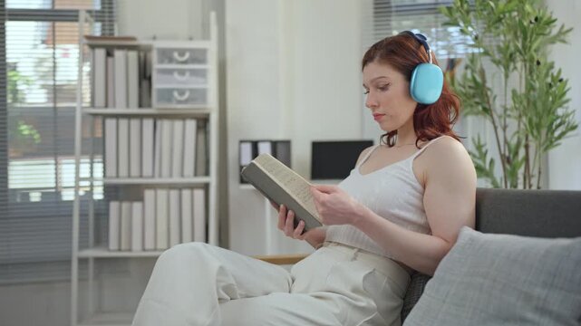 Young woman with headphones reading a book at home