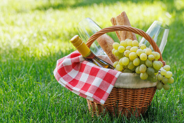 Obraz premium Picnic basket with wine, grapes, and baguette