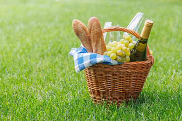 Obraz premium Picnic basket with wine, grapes, and baguette