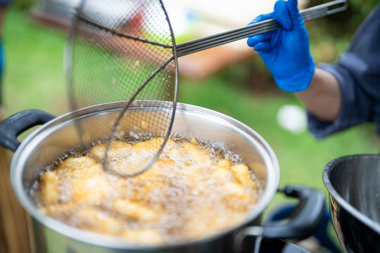 Deep frying hot oil street food outdoor cooking crispy snack hand blue glove boiling kitchen utensil metal pot golden food deep frying food hot oil outdoor cooking shows crispy snack preparation