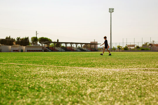 Young boy playing football on a green artificial turf field