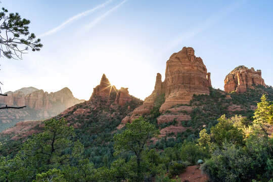 Starburst sun setting behind rock formations landscape