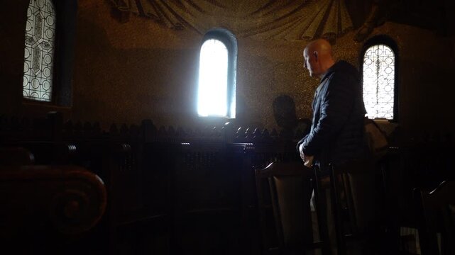 Cluj-Napoca, Romania A man walks in a small sunlit chapel in the Dormition of the Mother of God Metropolitan Cathedral