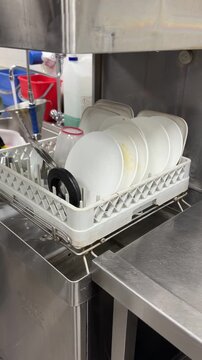 Worker loading plates into industrial dishwasher in a restaurant kitchen