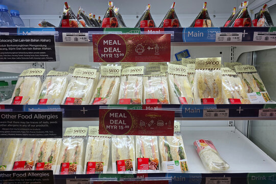 Penang, Malaysia - Jan 21, 2026: Various packaged sandwiches and Japanese onigiri arranged on refrigerated shelves with meal deal signage at WHSmith store in Penang International Airport.