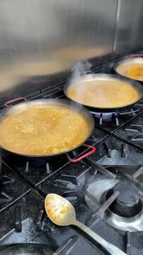 Restaurant chef cooking multiple paellas in a commercial kitchen
