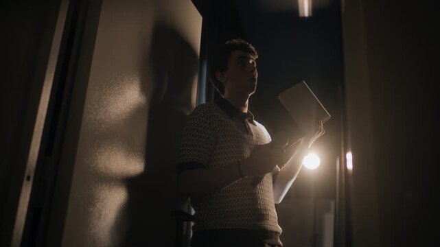 Low angle shot of young adult male stand up comic gesticulating while reciting speech standing backstage before live show