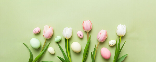 Happy Easter composition. Easter eggs on colored table with yellow Tulips. Natural dyed colorful...