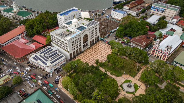 drone fly above downtown Iloilo City, Panay Island, Philippines revealing church and river urban cityscape