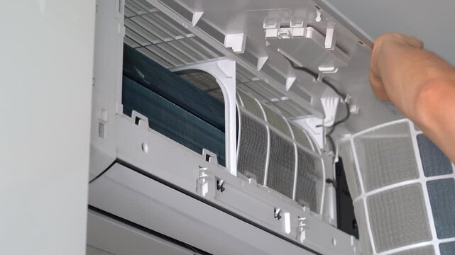 Hands change cleaning filter in air conditioner. Air conditioning maintenance. Purification and repair of cooling system