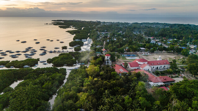 An aerial drone view looking over a traditional coastal village on Panglao Island, Bohol, Philippines. Red-roofed buildings