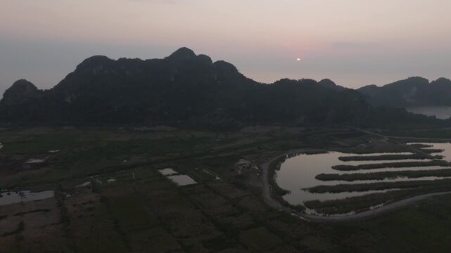 Cat Ba Vietnam drone flyover along a forested ridge above a valley town, with roads and fields stretching toward the coast.