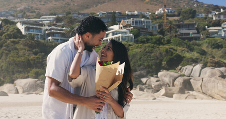 Fototapeta premium Smile, couple and hug with bouquet at beach for romantic date, celebration and bonding together. Happy, people and embrace with flowers for romance, anniversary getaway and surprise gift at seaside