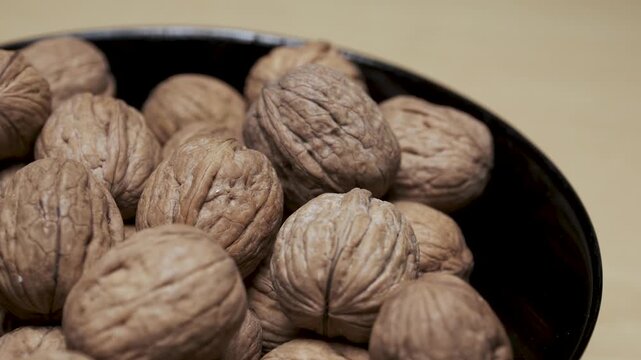 Overhead shot of whole walnuts in a dark round bowl texture and pattern