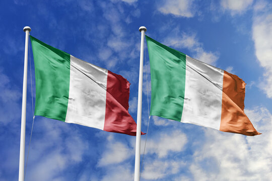 Italy and Ireland flags waving in a clear blue sky, symbolizing a powerful diplomacy, expanding global trade, a strategic partnership, and a shared vision of unity for a sustainable future.