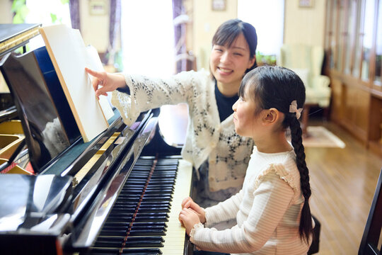 ピアノ教室でレッスンを行う先生と生徒の女の子