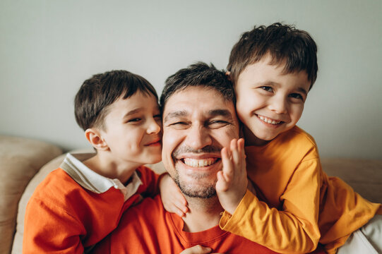 Father and sons embracing and smiling indoors showing unconditional love