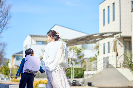 住宅街を手を繋いで歩く親子の後ろ姿