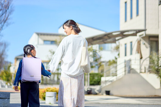 住宅街を手を繋いで歩く親子の後ろ姿