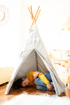 Young woman relaxing inside a cosy tipi tent at home