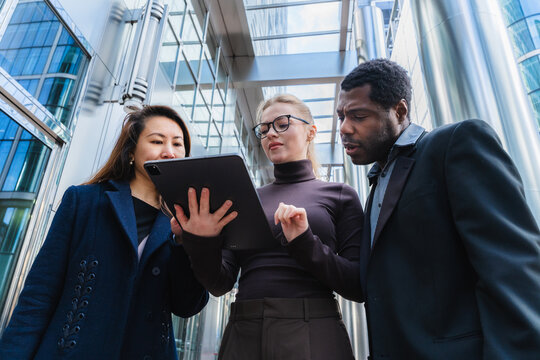 Business colleagues collaborating outdoors with tablet in urban setting