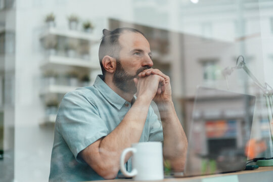Self-employed developer contemplating business strategy at window