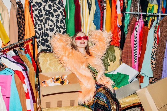 Trendy woman selling clothing online from colorful wardrobe indoors