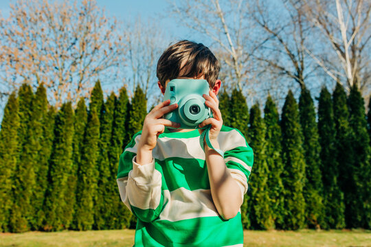 Child taking photograph with first camera outdoors in spring