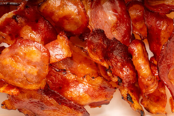 Close up shot Crispy fried bacon texture, Freshly cooked and golden brown fried bacon on black dish.  © MERCURY studio