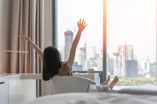 Life balance and summer holiday vacation concept with happy young woman taking a break, celebrating successful work done, casually resting in luxury city hotel workplace with computer laptop on desk