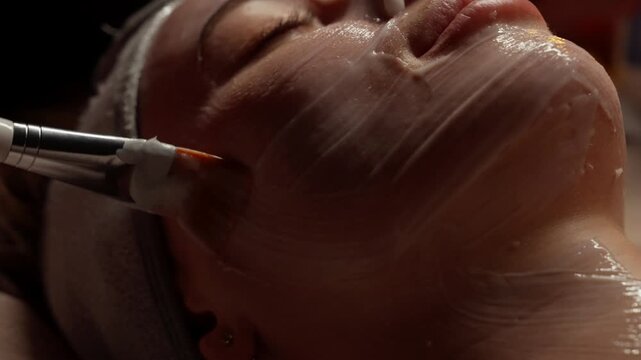 Closeup skincare treatment sequence showing relaxing facial mask application with soft brush strokes on face and neck in soothing spa wellness atmosphere